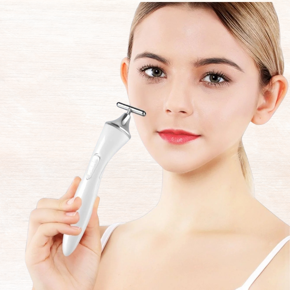 White T-shape microcurrent facial massager device held near cheek
