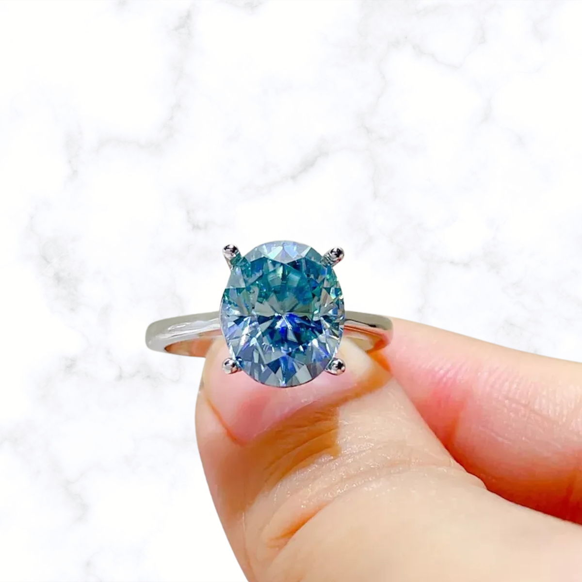 Sterling silver ring with blue moissanite oval center stone, four-prong setting