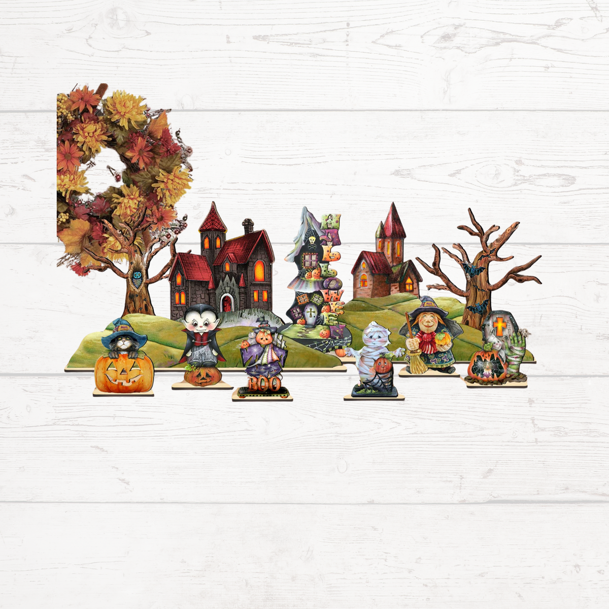 Halloween village figurine set with haunted houses, pumpkins, and characters on green hills.