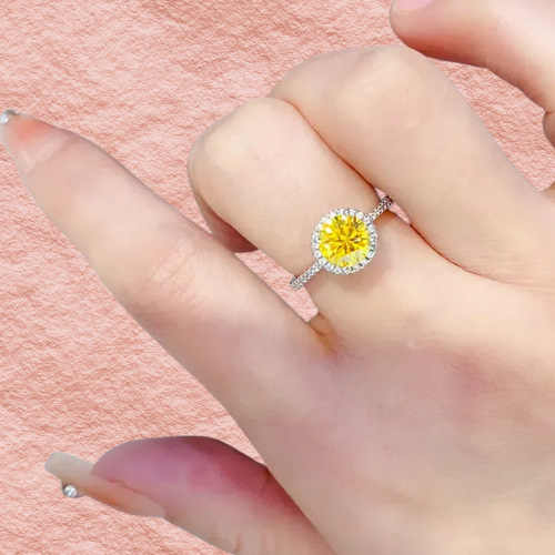 Round yellow moissanite halo ring in 925 sterling silver, shown on fingertip