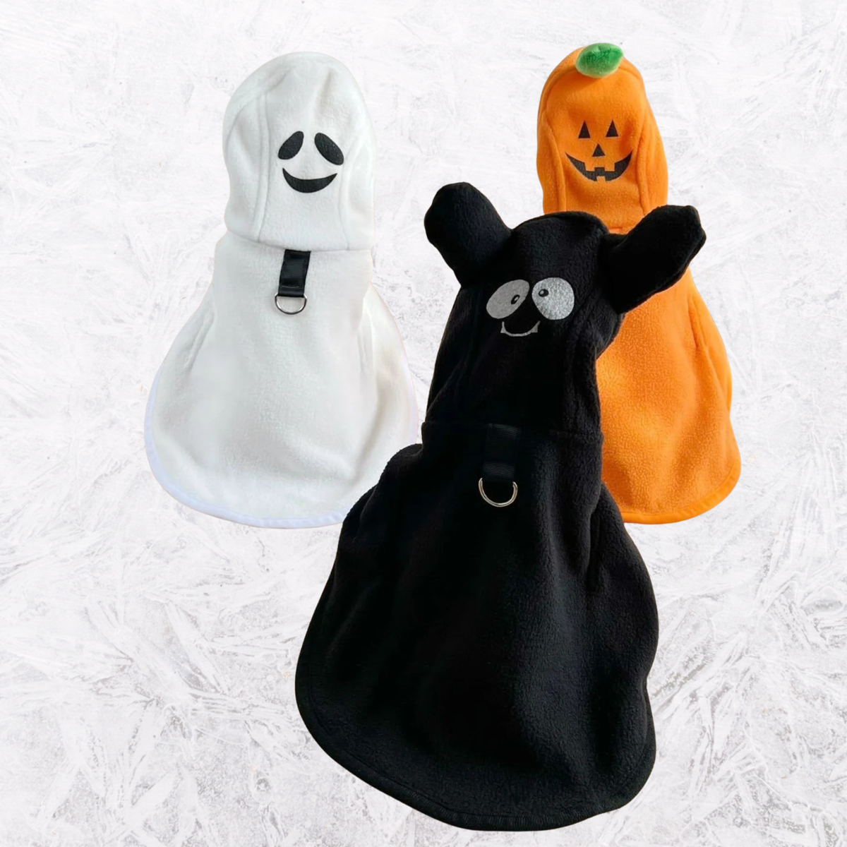 Three hooded pet costume coats: white smiling face, black cat face, orange jack-o’-lantern