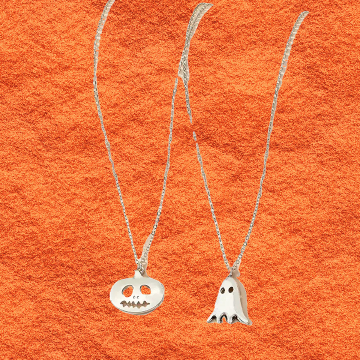 Silver pendant necklace duo with round jack-o-lantern charm and white ghost charm.