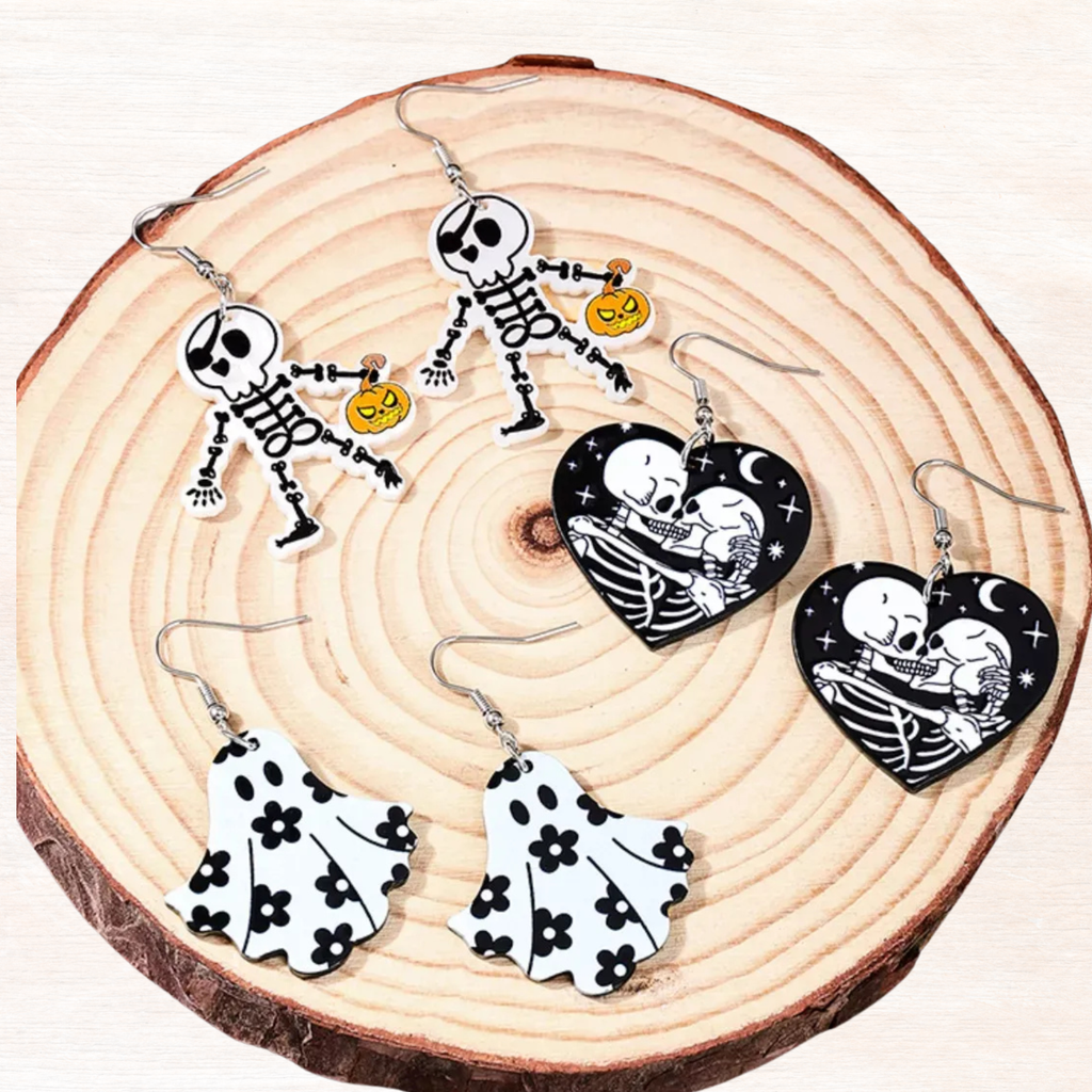 Halloween acrylic dangle earrings laid flat: skull-heart, ghost skirt, pumpkin skeleton