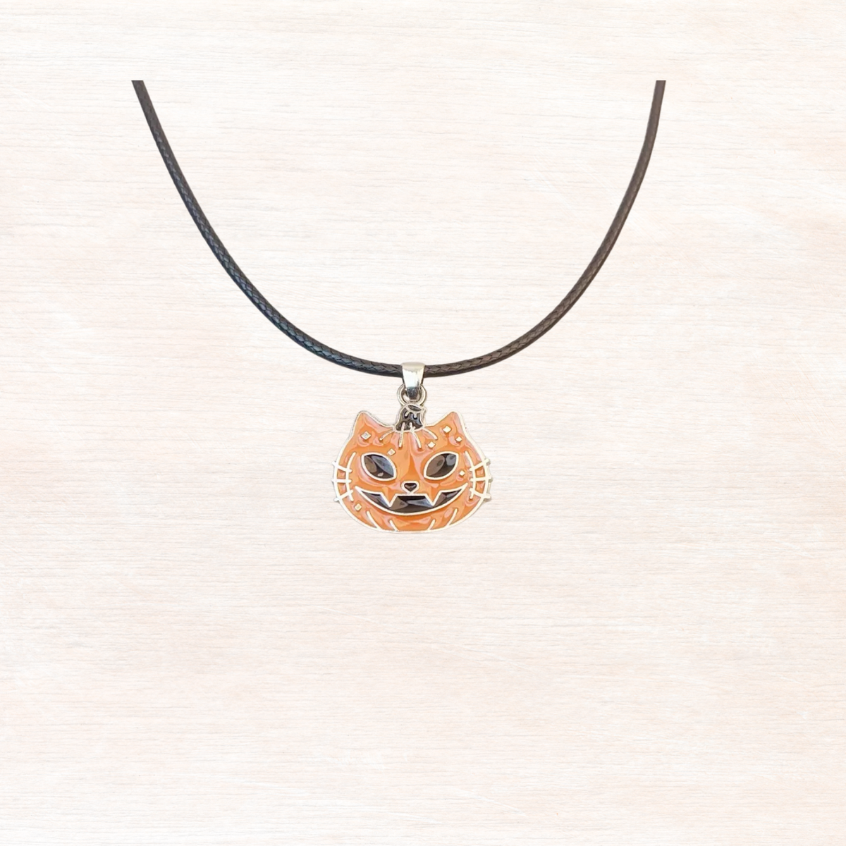 Halloween pumpkin pendant necklace with black cord and orange jack-o'-lantern charm
