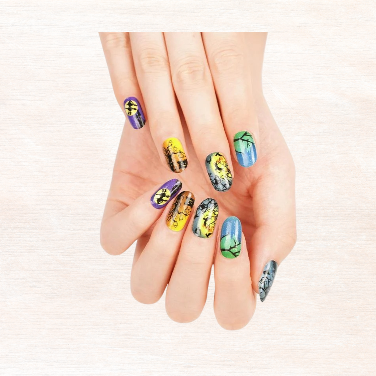 Halloween nail set on hand showing multiple patterned nails in yellow, blue, and purple