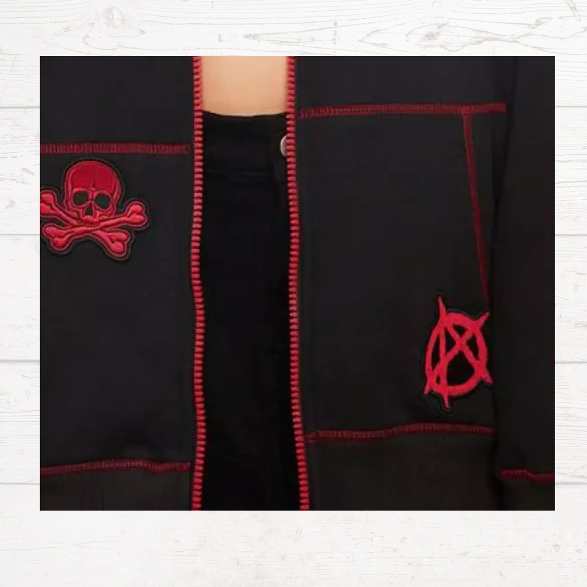 Black hoodie front with red/pink zipper, skull patch, and hood drawstrings.