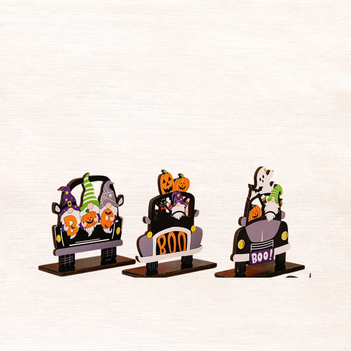 Three car-shaped Halloween ornaments on stands, each with 'BOO!' sign and jack-o'-lantern