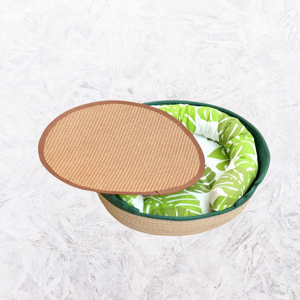Woven pet nest with dark green rim, brown woven top, lime leaf-pattern cushion.