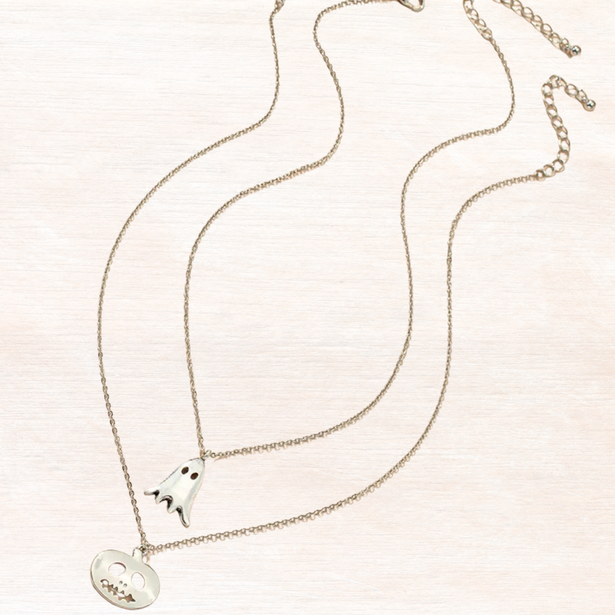 Silver necklace with ghost and pumpkin charms, silver-toned chain and enamel faces.