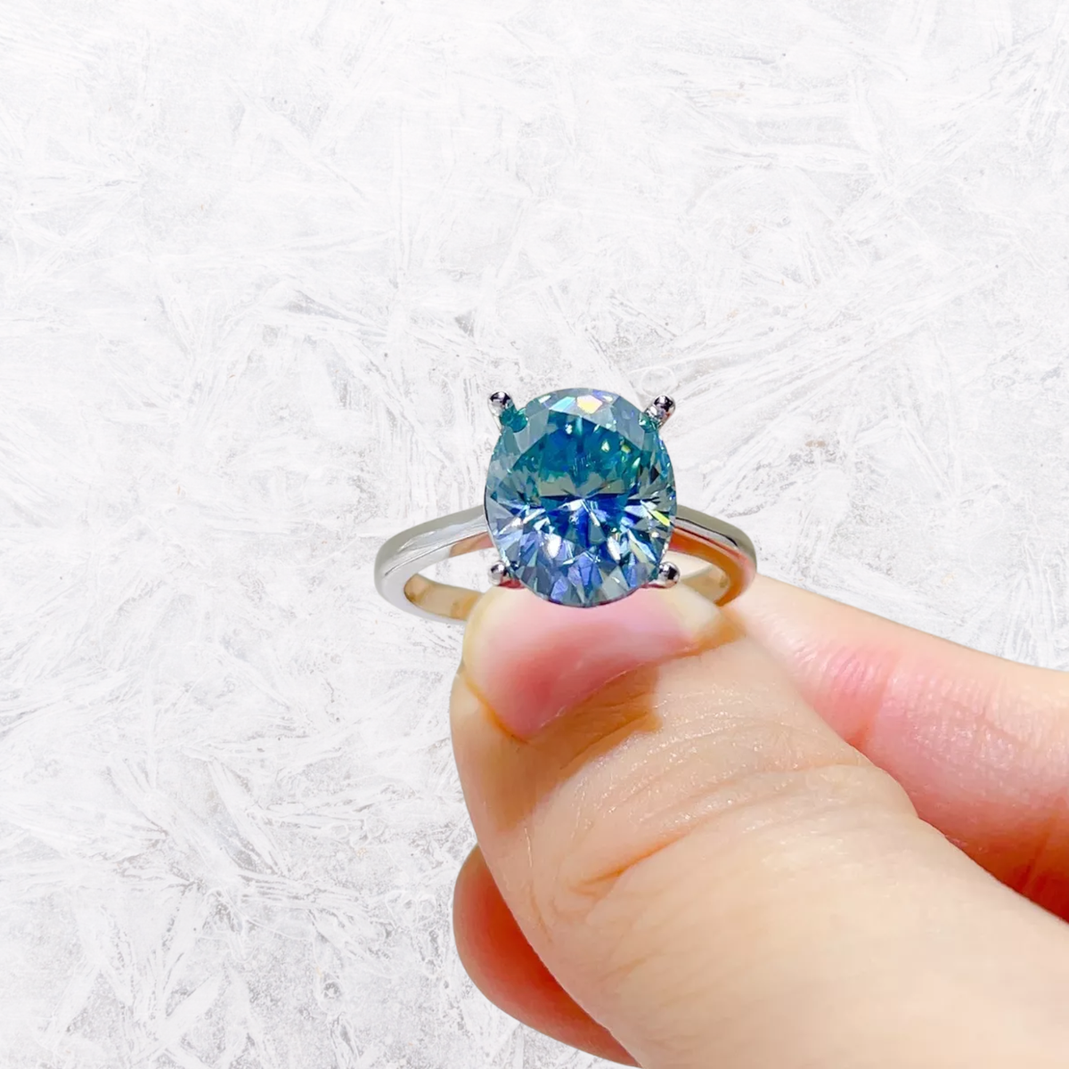Sterling silver moissanite ring with large blue oval center stone, four-prong bezel
