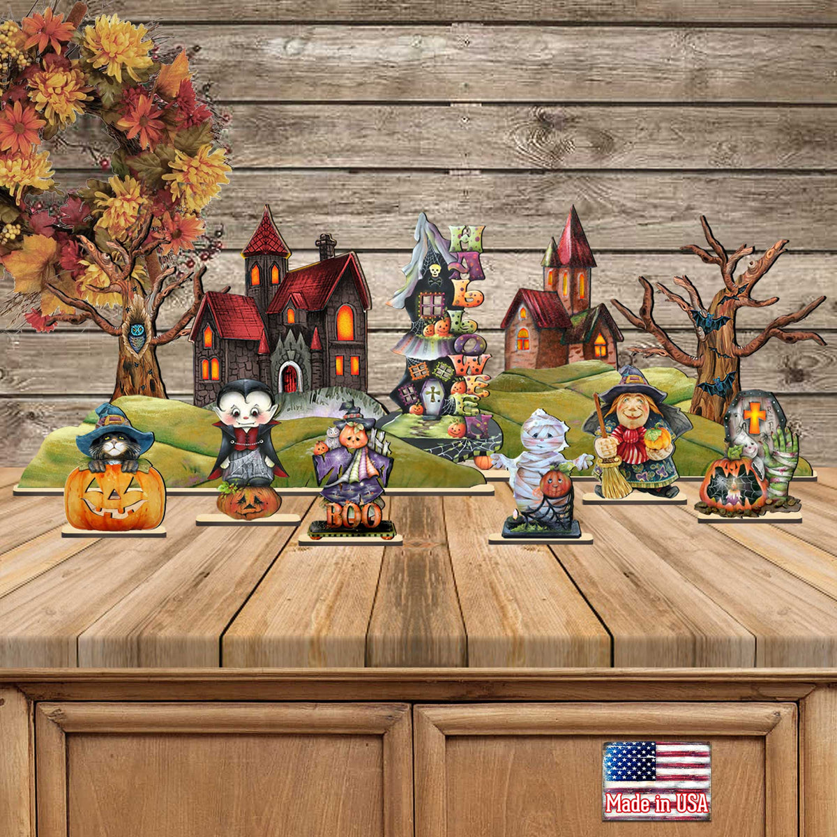 Halloween village figurine display on wooden platform with houses, pumpkins, and graveyard props.