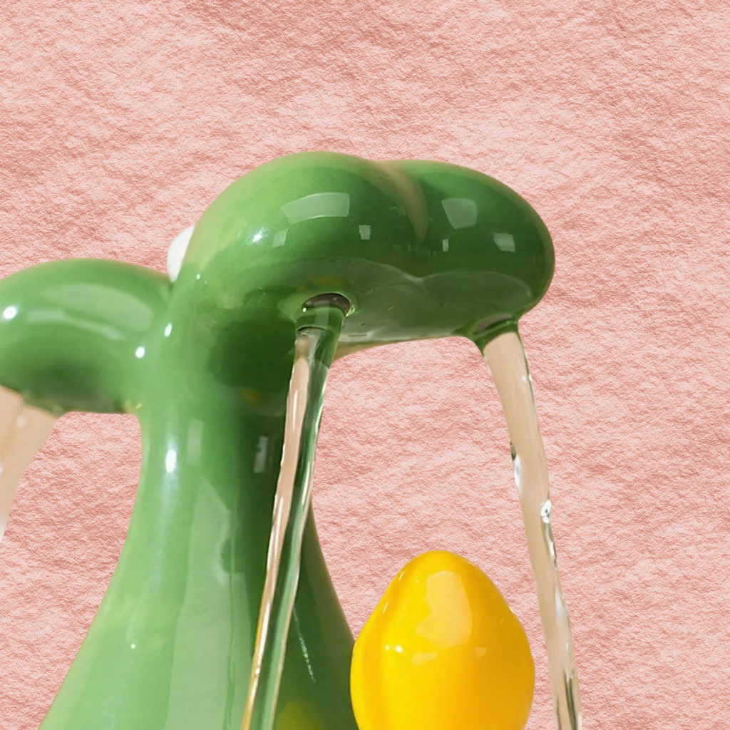 Green fountain spout with two streams and yellow drip outlet, close-up