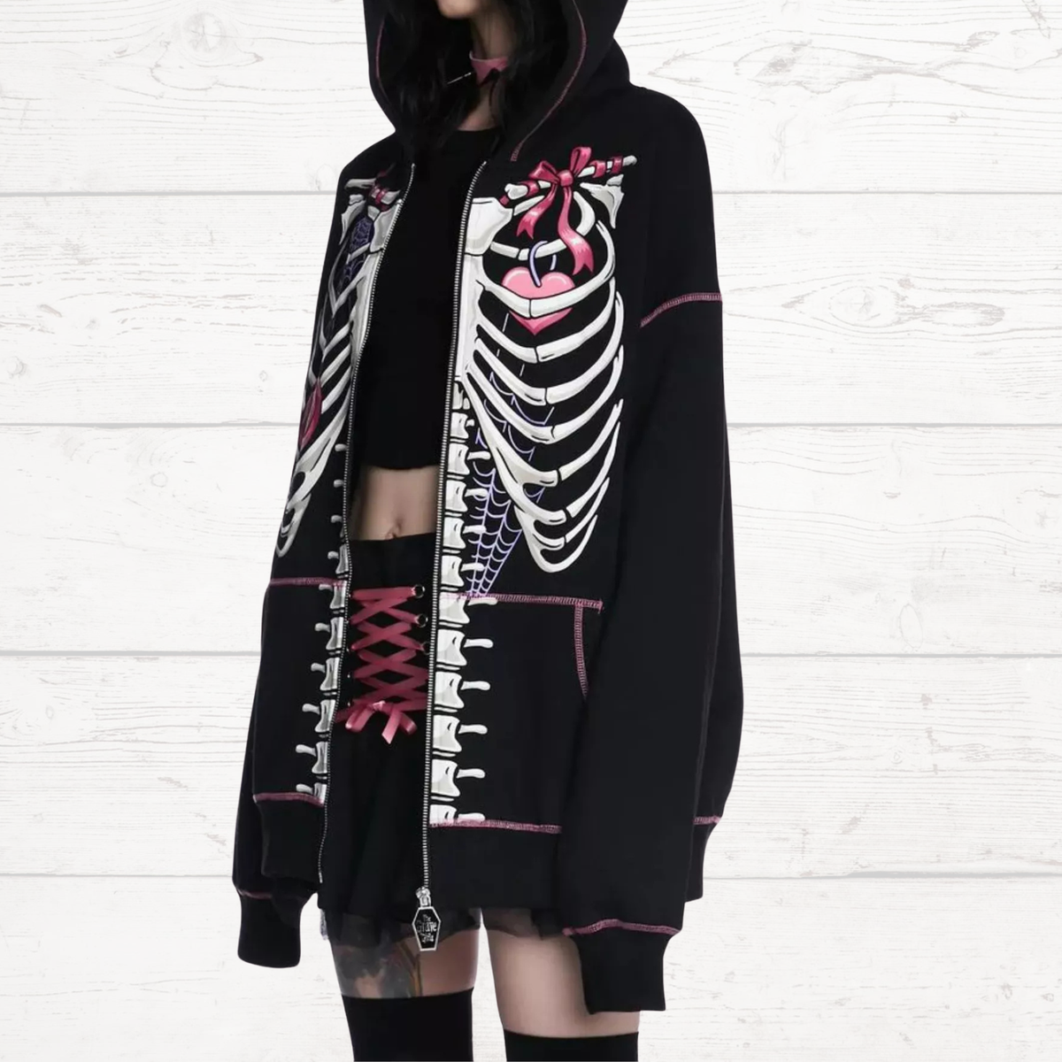 Black zip-up hoodie with skeleton print, hood up, and pink trim detail.