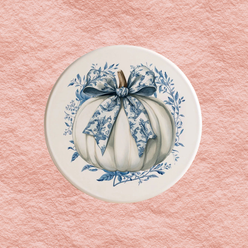 Round blue-and-white Halloween coaster with a bow pumpkin illustration and floral wreath border.