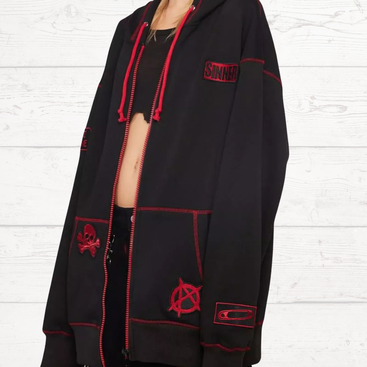 Black zip-up hoodie with red stitching, skull patch, and side pocket graphic.