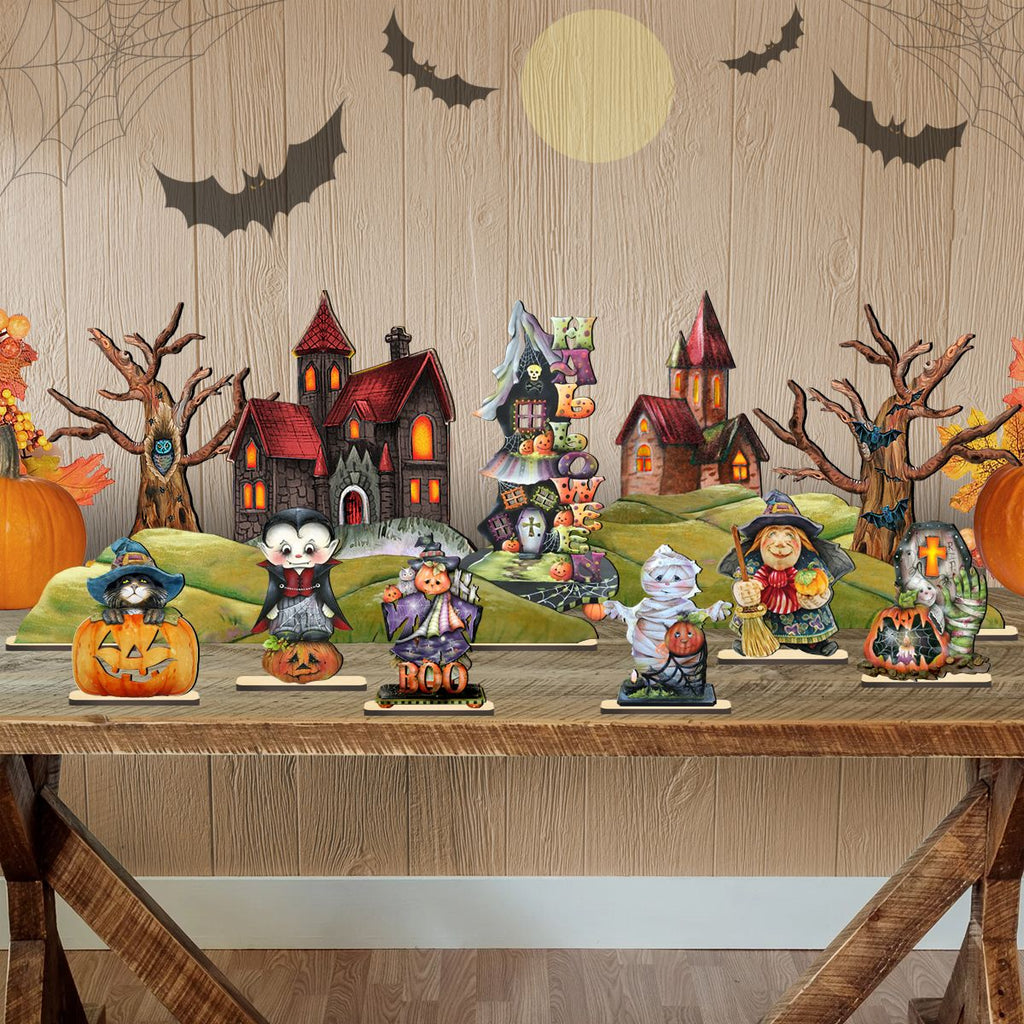 Halloween village figurine display on green hill bases with houses, bats, and pumpkins.
