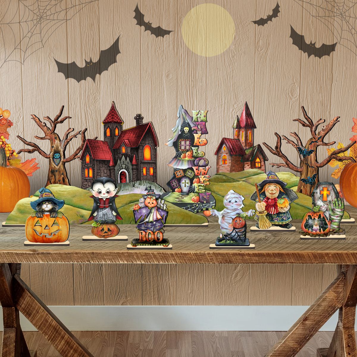 Halloween village figurine display on green hill bases with houses, bats, and pumpkins.