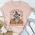 Heather peach Halloween graphic tee with raccoon in witch hat, pumpkins, and “Feral Girl” text